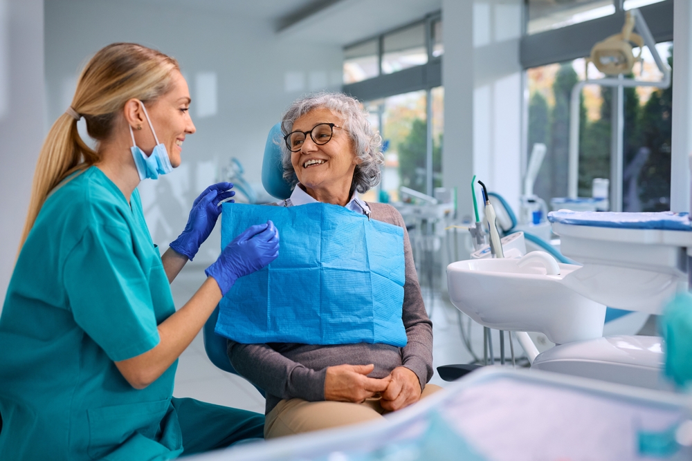Happy elderly woman talking to her orthodontist during appointment at dentist's office